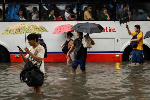  Người dân lội qua dòng nước ngập trên đường phố Manila (Philippines) ngày 17/8, khi mưa lớn do gió mùa trút xuống thủ đô, gây ngập úng trên diện rộng và làm gián đoạn sinh hoạt của người dân. 