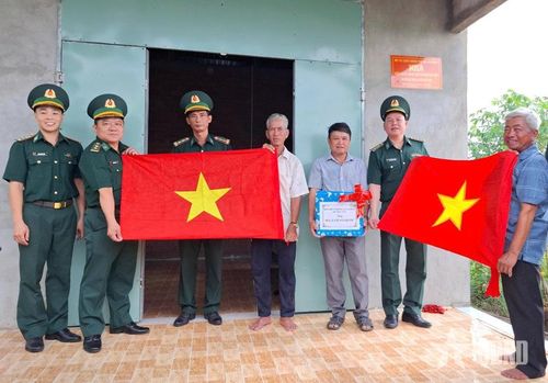 Thượng tá Phạm Thành Trung (thứ hai, từ phải sang) trao cờ Tổ quốc tặng Ban Quản lý dân cư ấp Voi Đình, xã Mỹ Quý, tỉnh Tây Ninh. Ảnh: VIỆT TIẾN