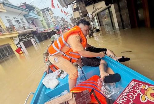 Một người dân bị mất sức do chống chọi với mưa lũ được lực lượng CSGT ứng cứu, đưa đi di tản.