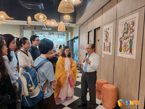TS. Nguyễn Ngọc Quận giải thích thêm về ý nghĩa các câu đối bằng chữ Nôm in trên các tranh vẽ dân gian tại triển lãm. Ảnh: H.D.