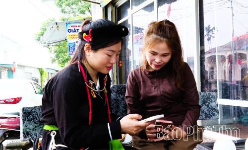 Đảng viên trẻ Tô Thị Thu Lan (bên trái) hướng dẫn người dân cài đặt, sử dụng các ứng dụng số trên điện thoại thông minh.
