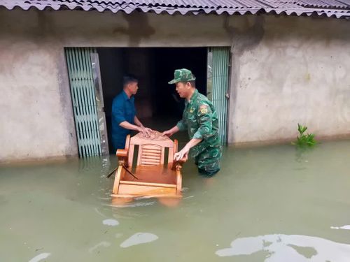 Cán bộ, chiến sĩ Đồn Biên phòng Đức Long hỗ trợ người dân xóm Nà Lạn, xã Đức Long di chuyển tài sản ra khỏi khu vực nhà bị ngập do mưa lớn.