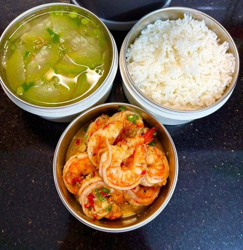 Hộp cơm gồm tôm sốt bơ tỏi đậm đà, ăn kèm canh bí xanh nấu tôm bằm thanh mát, vừa đủ cho một bữa trưa đủ dinh dưỡng, năng lượng cho cả ngày dài làm việc.