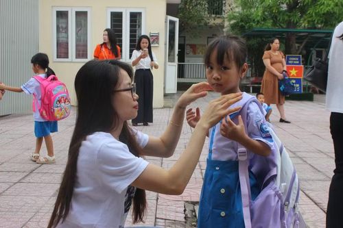Chị Tố Uyên phụ huynh học sinh lớp 1 (Trường Tiểu học Nam Hà) sửa soạn lại đồng phục cho con trước khi vào trường.