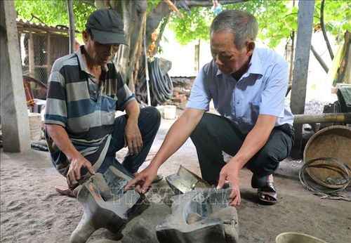 Ông Đỗ Đức Cảm (bìa trái) chia sẻ về quy trình sản xuất đồ đồng.