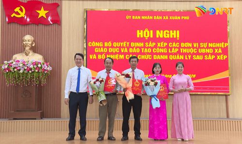 Lãnh đạo xã Xuân Phú trao quyết định và tặng hoa cho tập thể lãnh đạo Trường THCS Xuân Phú. Ảnh: LAM KHUÊ