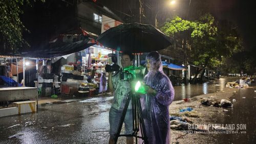 Phóng viên Hoàng Huấn và Hoàng Yến (Báo và PTTH Lạng Sơn) tác nghiệp trong mưa bão ghi nhận thông tin tại khu vực chợ Giếng Vuông (phường Kỳ Lừa)