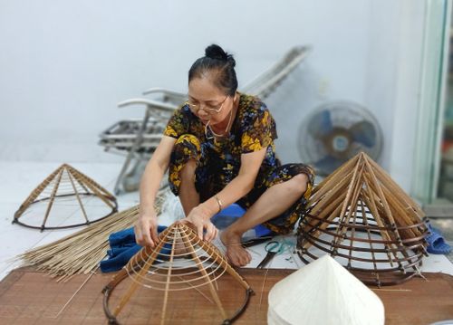 Bà Nguyễn Thị Quyết say mê gắn từng chiếc vòng vào khung nón. Ảnh: Hoàng Quyết