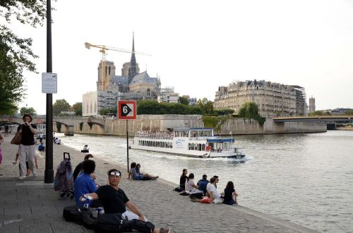 Người dân và du khách ngồi thư giãn bên bờ sông Seine, phía xa là Nhà thờ Đức Bà Paris. Ảnh: Hữu Chiến - PV TTXVN tại Pháp