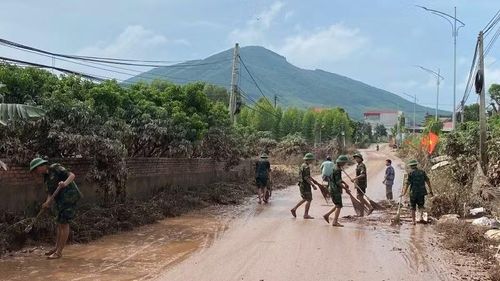 Lực lượng quân đội dọn dẹp bùn đất sau lũ. (Ảnh: ĐG)