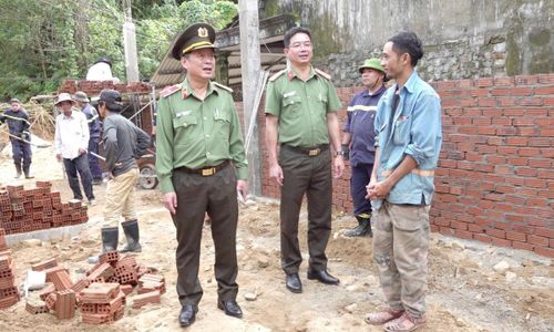 Thiếu tướng Nguyễn Hữu Hợp (trái) động viên người dân vùng lũ đang được lực lượng Công an hỗ trợ xây nhà mới để ổn định cuộc sống.
