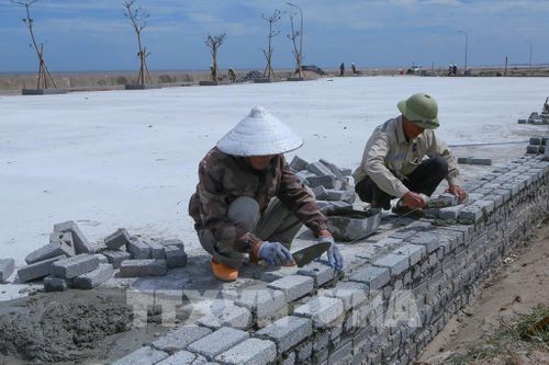 Công nhân xây dựng hạ tầng vỉa hè góp phần tạo diện mạo sạch đẹp, đồng bộ hơn cho không gian ven biển xã Giao Ninh. Ảnh: Công Luật - TTXVN