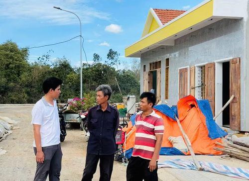 Ông Lâm Văn Tân (bên trái) - Bí thư Chi bộ tổ dân phố Tiên Hội (phường An Nhơn Bắc) thăm hỏi người dân bị ảnh hưởng bởi Dự án đường bộ cao tốc Quy Nhơn - Pleiku đang xây dựng lại nhà cửa tại khu tái định cư. Ảnh: N.Q