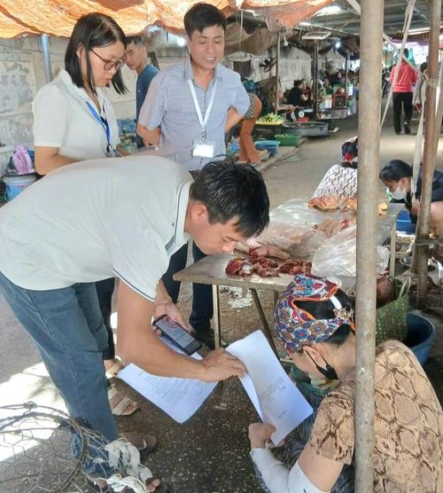 Lực lượng chức năng xã Hòa Xá hướng dẫn các hộ kinh doanh tại chợ ký cam kết an toàn thực phẩm. Ảnh: TTVH