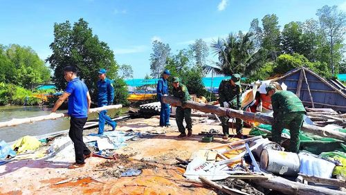 Biên phòng Đất Mũi cùng lực lượng tại chỗ vận chuyển cột nhà bị sập đưa ra vị trí tập kết. (Ảnh: Hoàng Tá)