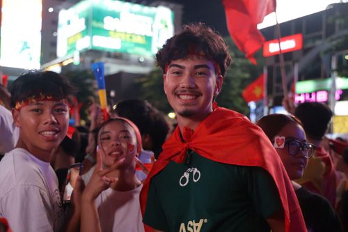 Các du khách nước ngoài khoác cờ đỏ sao vàng, chia sẻ niềm vui với cổ động viên Việt Nam.