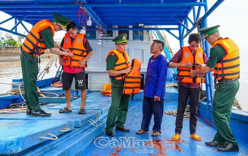 Cán bộ, chiến sĩ Ðồn Biên phòng Gành Hào hướng dẫn ngư dân sử dụng áo phao đúng cách.