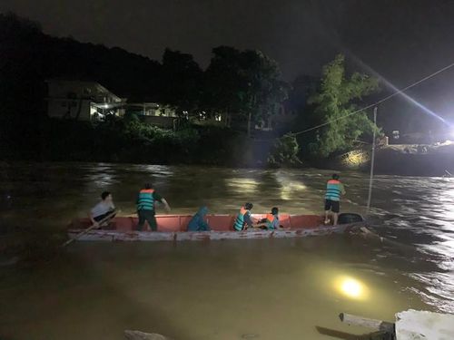 Lực lượng chức năng dùng thuyền vượt dòng nước chảy xiết trong đêm, đưa bệnh nhân qua sông an toàn giữa lúc mưa lũ gây chia cắt. ẢNH: Q.S