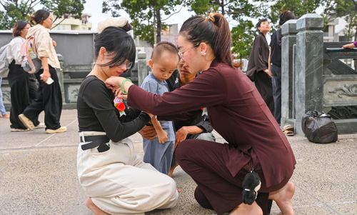 Phật tử cài hoa đỏ để trân trọng những ngày tháng còn được ở bên đấng sinh thành. Ảnh: MẠNH THẮNG