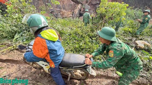 Cán bộ, chiến sĩ Đồn Biên phòng Chiềng Tương hỗ trợ nhân dân qua lại khu vực đoạn đường bị sạt lở. Ảnh: Quàng Hùng