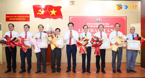 Phó Bí thư Thường trực Thành ủy, Bí thư Đảng ủy Các cơ quan Đảng thành phố Nguyễn Khắc Toàn (thứ 5, bên phải sang) trao Huy hiệu 35 năm tuổi Đảng cho các đảng viên đủ tiêu chuẩn. Ảnh: NGỌC PHÚ