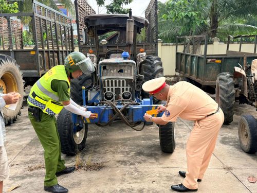 Cán bộ Trạm Cảnh sát giao thông Hàm Tân dán miếng phản quang cho xe tự chế của người dân