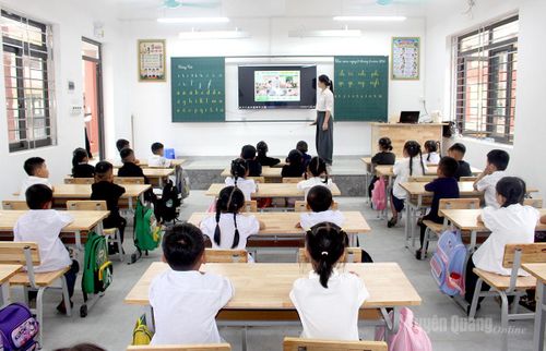 Các em học sinh khối tiểu học chăm chú theo dõi cô giáo phổ biến nội quy của trường, lớp.