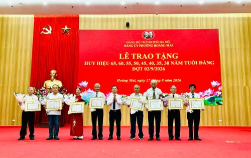 Ủy viên Ban Thường vụ Đảng ủy, Chủ tịch Ủy ban MTTQ Việt Nam phường Hoàng Mai Triệu Hải Vân trao Huy hiệu Đảng tặng các đảng viên 50 năm tuổi Đảng. Ảnh: Trần Oanh.