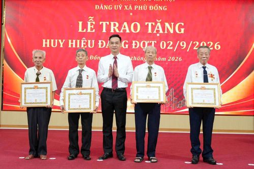 Đồng chí Nguyễn Mậu Quang, Phó Bí thư Thường trực Đảng ủy xã trao Huy hiệu 65 năm tuổi Đảng cho các đồng chí đảng viên. Ảnh: Nguyễn Sơn