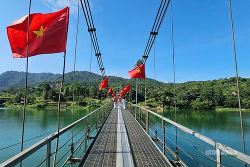 Hàng cờ đỏ sao vàng trải dài theo nhịp cầu bắc qua sông Chu. Ảnh: T.Anh