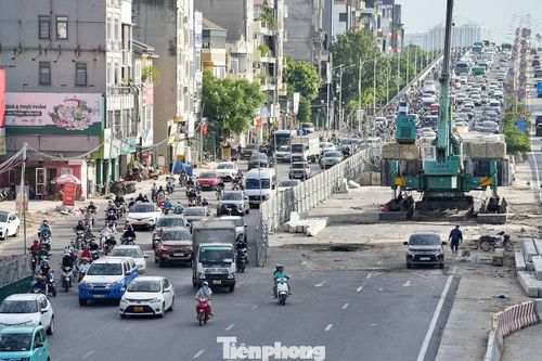 Tại khu vực nút giao Cổ Linh - Thạch Bàn, phương tiện xếp thành hàng dài chờ qua nút. Ôtô nối đuôi nhau, trong khi xe máy len qua những khoảng trống để tìm hướng di chuyển.