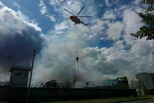 Một trực thăng chữa cháy thả nước xuống một nhà kho bị tập kích tại Kyiv, Ukraine ngày 27-8-2026. Ảnh: Reuters