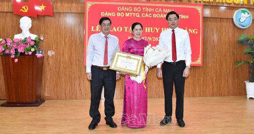 Đồng chí Phạm Minh Luyến, Phó Bí thư Đảng uỷ MTTQ, các đoàn thể tỉnh (bên phải) và đồng chí Trương Dũng Tiến, Phó Chủ tịch Uỷ ban MTTQ Việt Nam tỉnh Cà Mau, Chủ tịch Hội Cựu chiến binh tỉnh, trao Huy hiệu 50 năm tuổi Đảng và tặng hoa chúc mừng đồng chí Võ Thị Hồng Thoại.