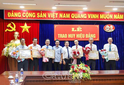 Hai Phó Bí thư Đảng uỷ UBND tỉnh Lê Bình Nguyên (bên trái) và Lê Hoài Bảo trao Huy hiệu 35 năm tuổi Đảng và tặng hoa chúc mừng các đảng viên.