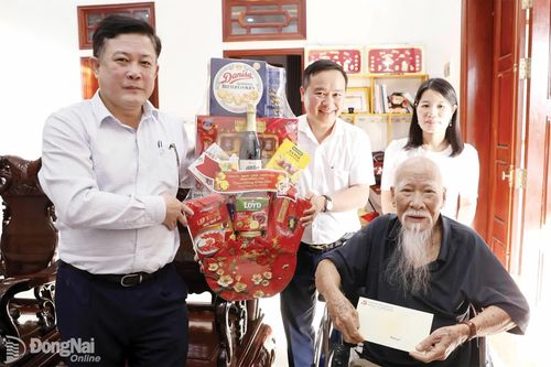 Đồng chí Đặng Hà Giang (bìa trái), Thành ủy viên, Bí thư Đảng ủy, Chủ tịch HĐND xã Thiện Hưng thăm, tặng quà cụ Huỳnh Thế Thiện (đảng viên 76 năm tuổi Đảng).