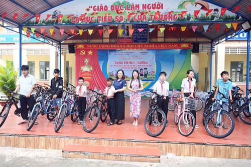 Bí thư Chi bộ Phòng Dịch vụ - Quảng cáo Nguyễn Thị Phượng và Phó Chủ tịch UBND xã Nha Bích Nguyễn Thị Minh Tiền tặng xe đạp cho các học sinh có hoàn cảnh khó khăn. Ảnh: Thu Hiền