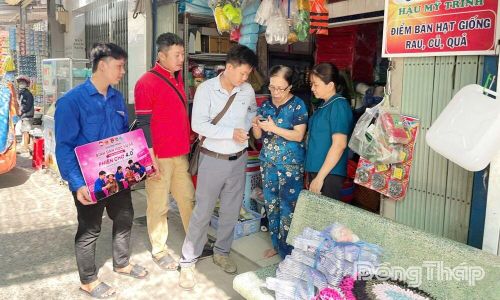 Đoàn viên, thanh niên hướng dẫn tiểu thương chợ Hậu Mỹ Trinh tạo và sử dụng mã QR thanh toán không dùng tiền mặt.