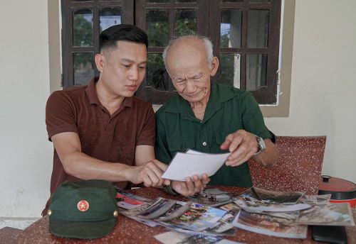 Ông Lê Văn Phước xem lại những hình ảnh và tư liệu trong quá trình trò chuyện về những năm tháng quân ngũ.