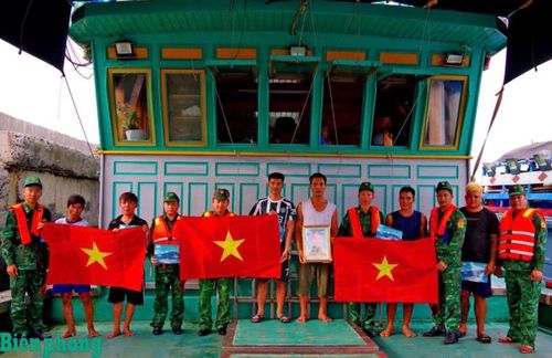 Cán bộ Hải đoàn Biên phòng 38 tuyên truyền pháp luật, tặng cờ Tổ quốc và ảnh Bác Hồ cho ngư dân. Ảnh: Văn Vinh