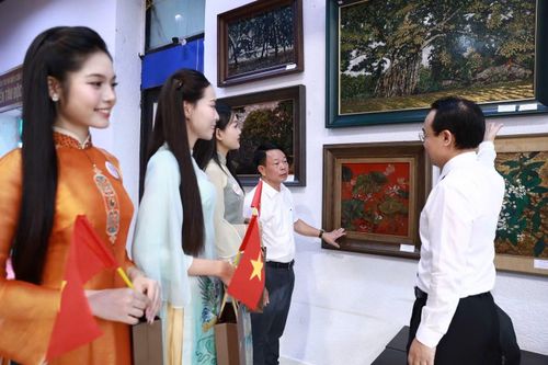 Ông Nguyễn Quốc Vượng - Phó Tổng Giám đốc Tập đoàn Đường sắt quốc gia Việt Nam (bìa phải) - giới thiệu với nhà báo Phùng Công Sưởng - Tổng Biên tập Báo Tiền Phong, Trưởng Ban tổ chức Hoa hậu Việt Nam 2026 - và một số thí sinh về các tác phẩm trưng bày tại triển lãm.
