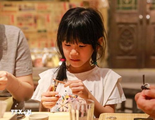 Khách tham quan trải nghiệm làm dép lốp. (Ảnh: Khánh Hoà/TTXVN)