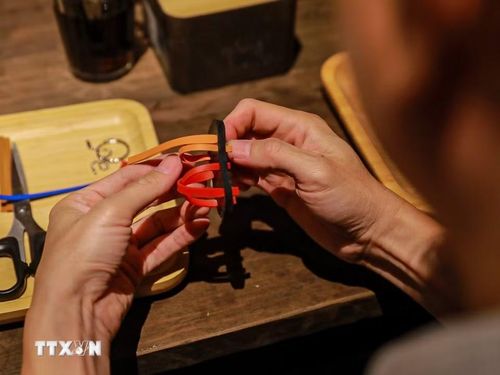 Khách tham quan trải nghiệm làm dép lốp. (Ảnh: Khánh Hoà/TTXVN)