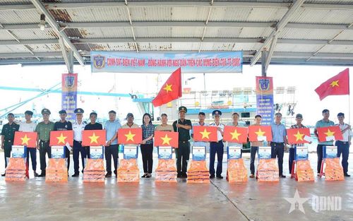 Đại diện Vùng Cảnh sát biển 3 phối hợp trao cờ Tổ quốc, áo phao và quà tặng ngư dân. 
