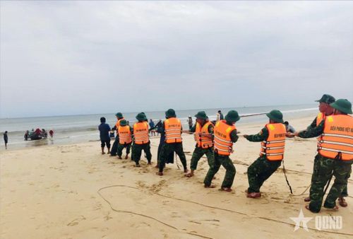Cán bộ, chiến sĩ Đồn Biên phòng cửa khẩu cảng Cửa Việt (Ban chỉ huy BĐBP tỉnh Quảng Trị) hỗ trợ ngư dân xã Cửa Việt kéo thuyền bị chìm vào bờ. Ảnh: HOÀI NAM