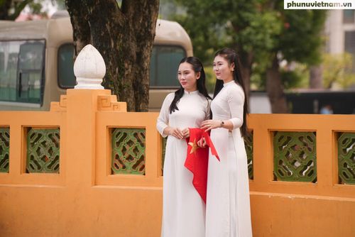 2 cô gái trong tà áo dài trắng cầm cờ Tổ quốc, lưu lại những khoảnh khắc đáng nhớ trong dịp kỷ niệm các ngày lễ lớn của đất nước.