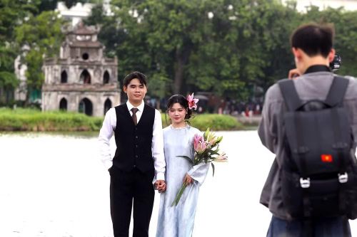 Đôi bạn trẻ tranh thủ chụp ảnh bên Hồ Gươm, ghi dấu một ngày nghỉ lễ đáng nhớ.