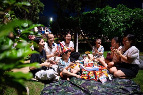 Chị Phạm Thuỳ Trang (bên phải, phường Phú Lương) cùng gia đình lần đầu tổ chức sinh nhật cho con Minh Đức (6 tuổi) tại điểm xem pháo hoa tại Mỹ Đình. Cả nhà chuẩn bị bánh kẹo, đồ ăn vặt từ chiều và có mặt tại điểm xem trên đường Lê Quang Đạo lúc 19h.