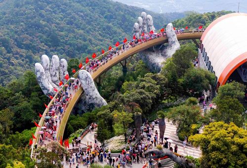 Một trong những trải nghiệm được nhiều du khách chờ đợi là check-in tại Cầu Vàng. Công trình biểu tượng nằm ở độ cao 1.487m được trang hoàng bằng hàng trăm lá Quốc kỳ, nổi bật giữa biển mây và núi rừng