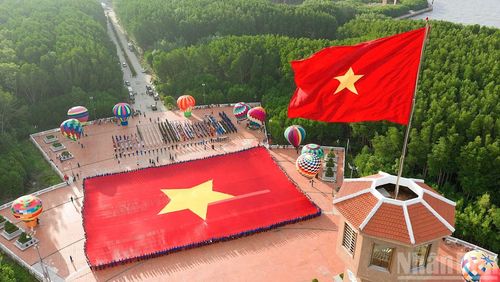 Lá cờ Tổ quốc kiêu hãnh tung bay trên đỉnh Cột cờ Hà Nội tại Đất Mũi, phía dưới là đại kỳ kỷ lục được hàng trăm đoàn viên, thanh niên Cà Mau giữ vững. (Ảnh: HỮU TÙNG)