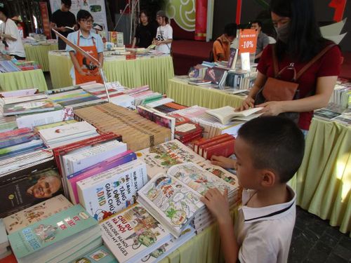 Các bạn nhỏ chăm chú lật mở từng trang sách ngay tại gian hàng để tự tay chọn lựa những đầu sách kỹ năng bổ ích cùng các tập truyện tranh thiếu nhi phù hợp với lứa tuổi của mình. (Ảnh: Bảo Châu)